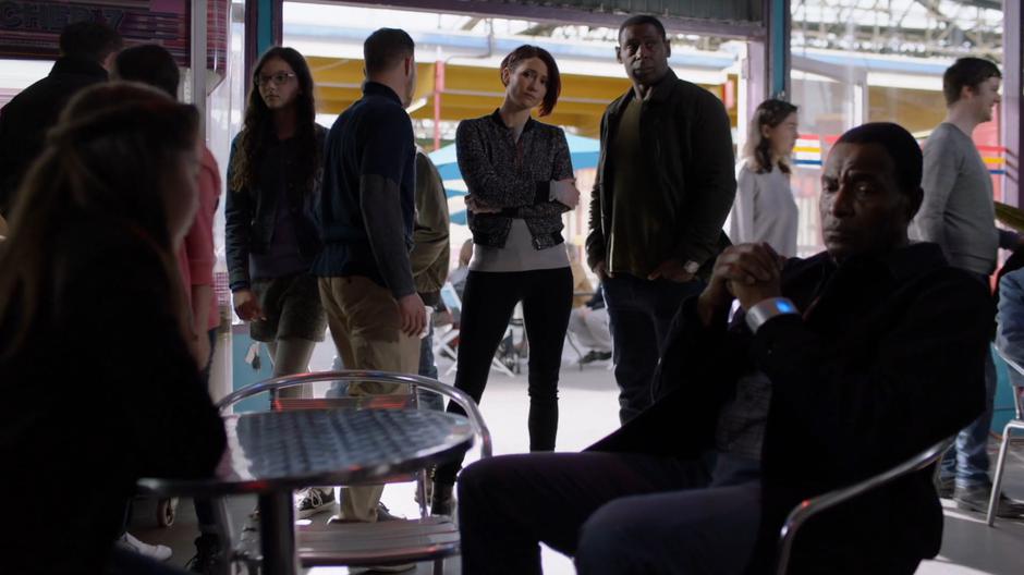 Alex and J'onn look at Ruby and M'yrnn who are both sitting morosely at a table.