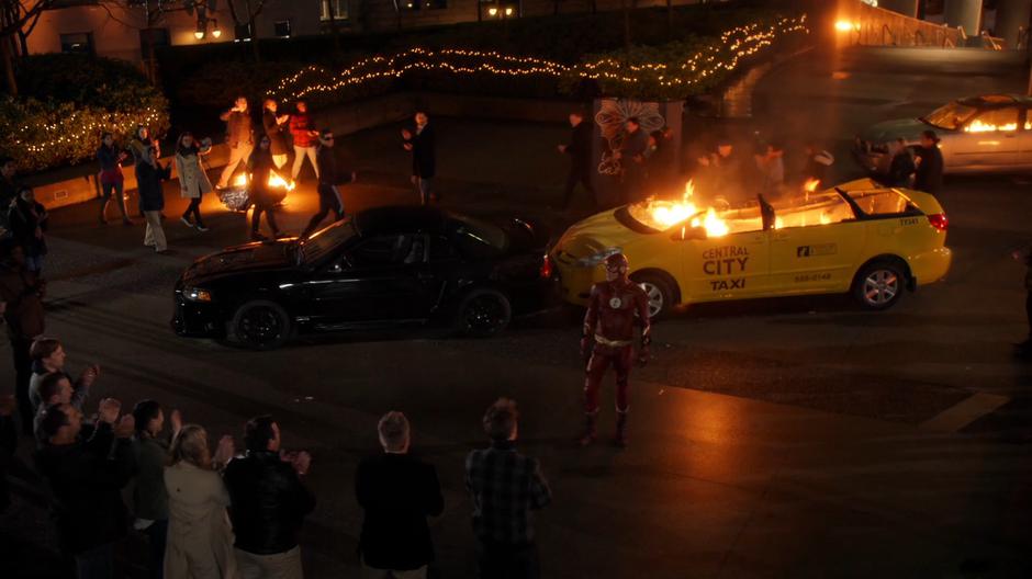 Barry stands in the middle of the crowd as their cheer him for saving their lives.