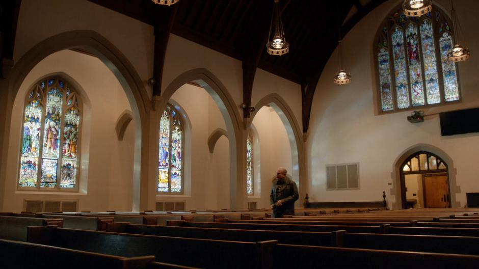 Detective Benedetto walks down the aisle of the church to the confessional.