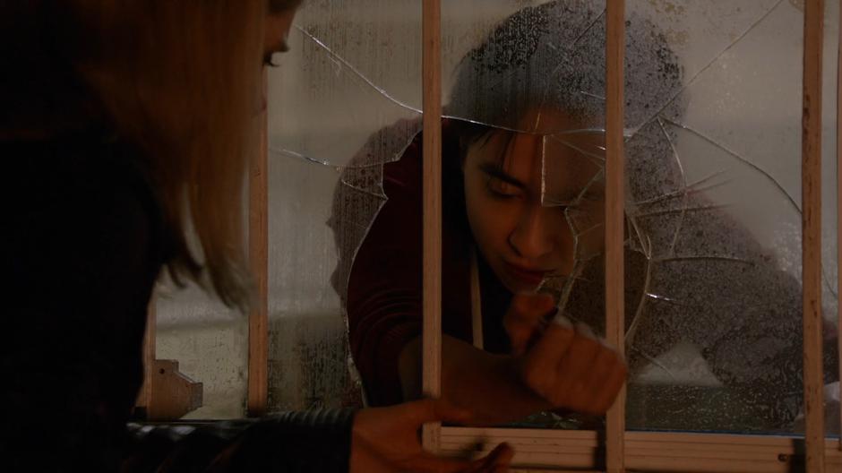 Curtis holds his arm out through the broken kitchen window for Liv to scratch.