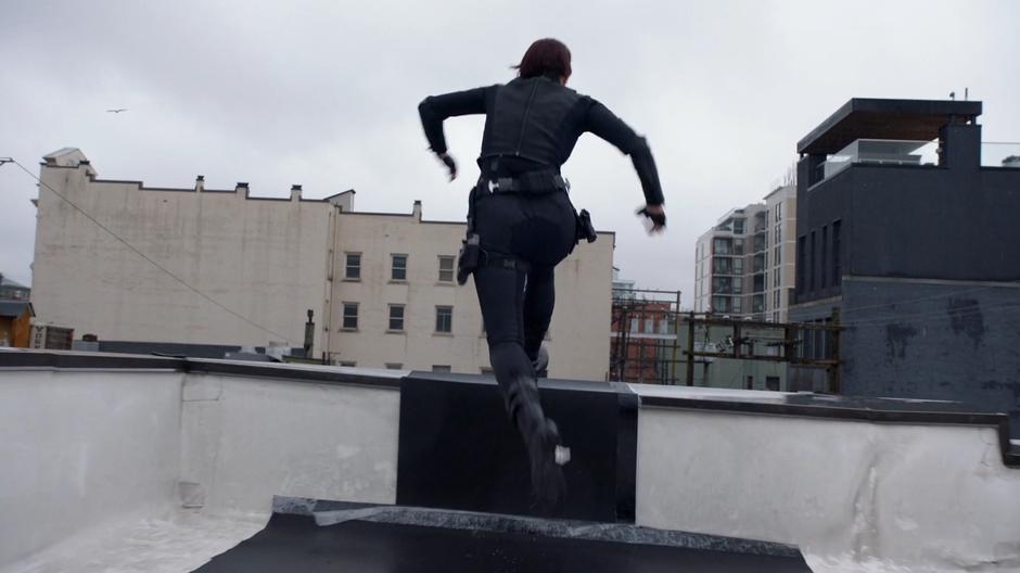 Alex leaps over the edge of the roof.