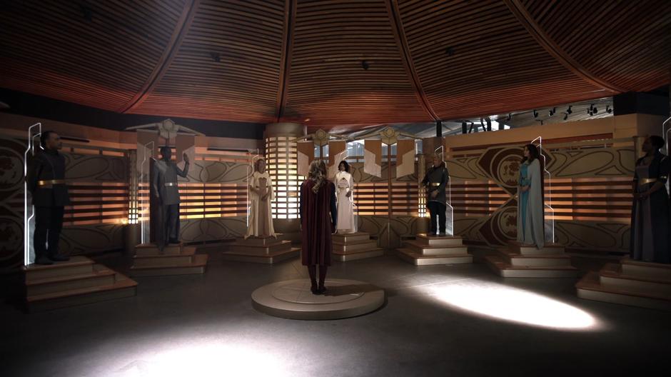 Kara stands on the center of the chamber while the council votes on her request.