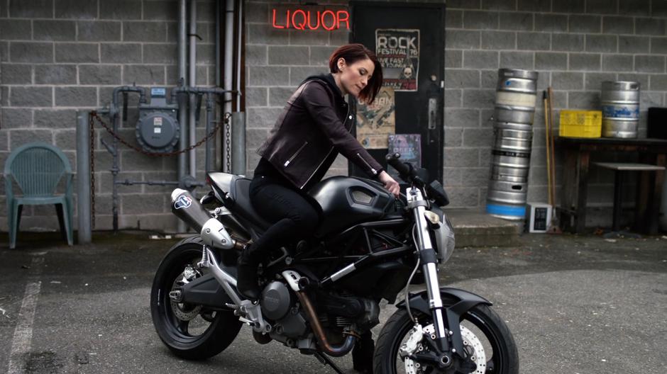 Alex turns on her motorcycle out behind the bar.