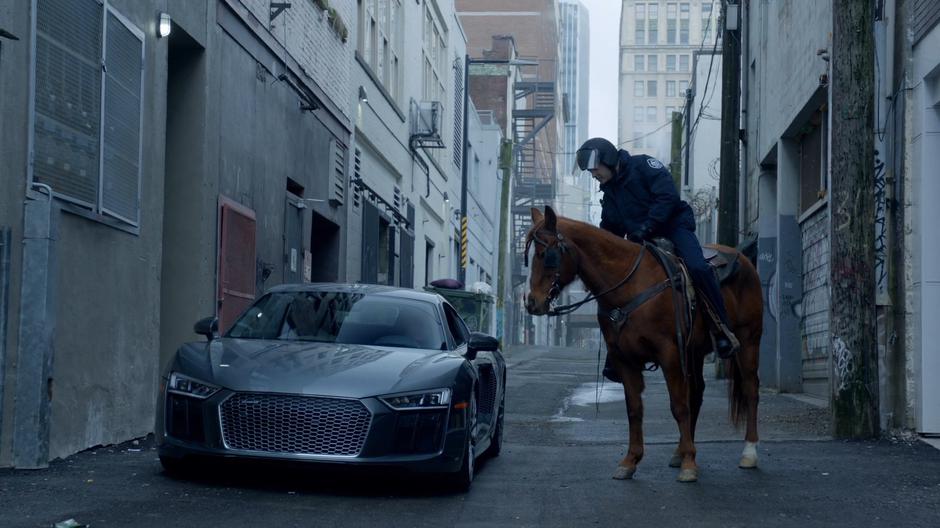 A police officer on horseback leans down to tell Blaine that he cannot park his car in the alley.