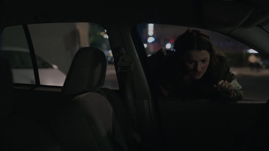 O'Reilly leans into the driver's side window of her car to listen to the radio.