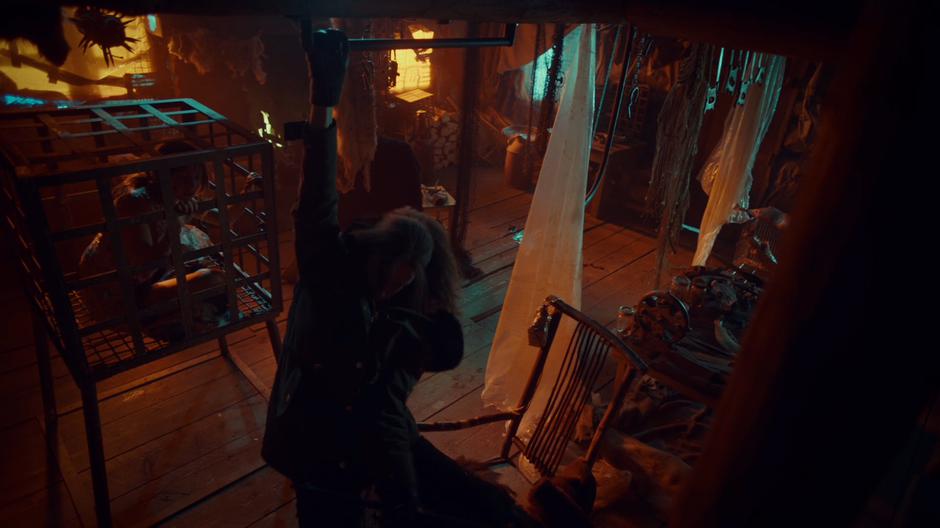 Wynonna grabs a pipe to pull herself up to the second floor while Waverly watches from the cage.
