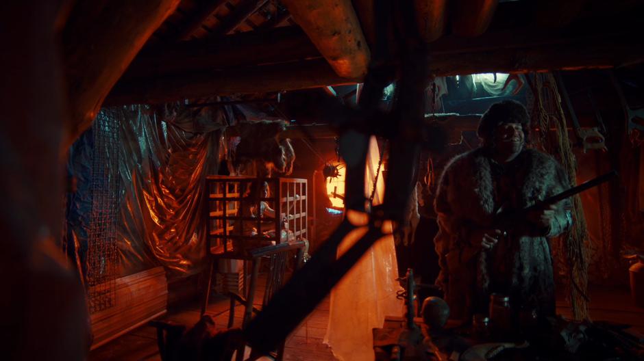 The Revenant looks around the cabin for intruders while Waverly watches from her cage.