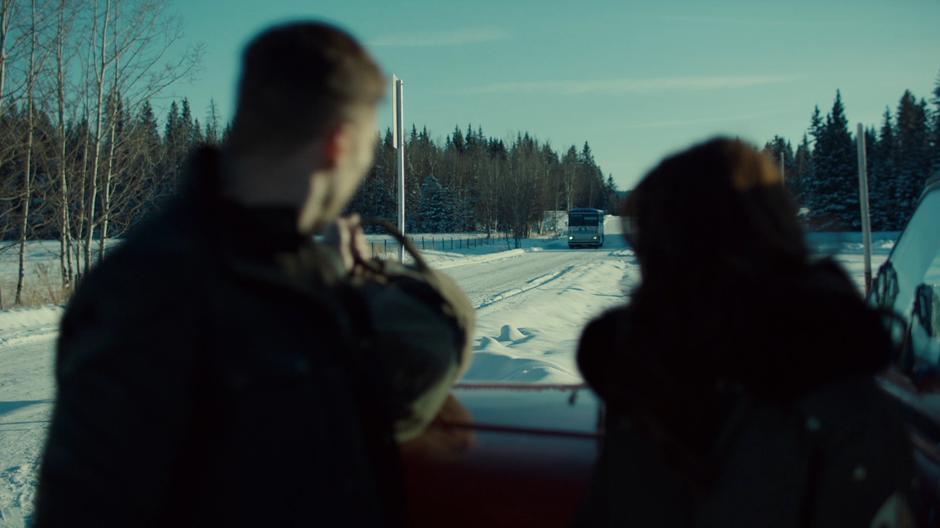 Quinn and Wynonna look over as the bus pulls up to the station.