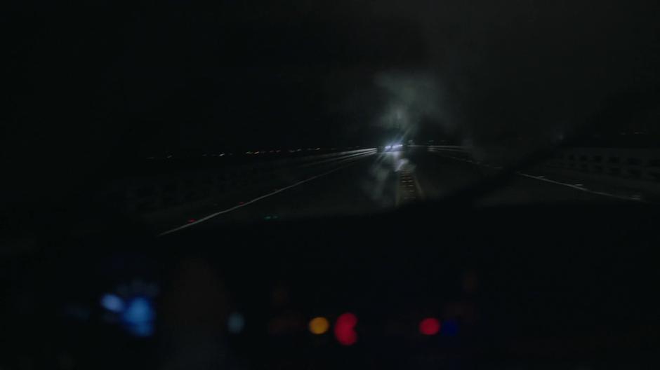 The car drifts into the oncoming lane while driving down the dark bridge.