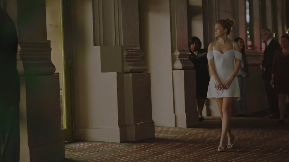 Tandy looks at the theater as she walks down the sidewalk in her nice white dress.