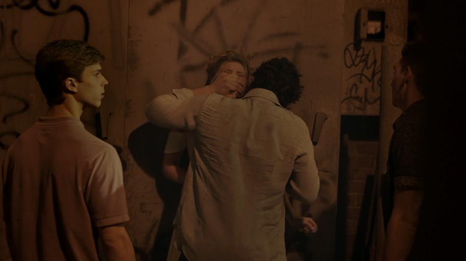 Rick's friends share a look while Rick pushes Tandy against the wall of the alley and holds his hand over her mouth.