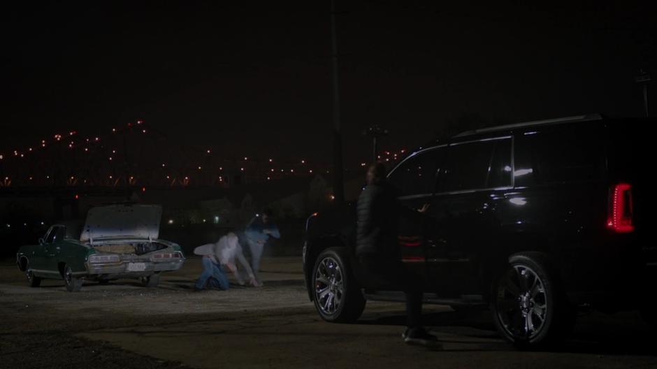 Tyrone pushes Connors to the side after jumping out of the trunk while the guy looking to buy from him runs into his SUV.