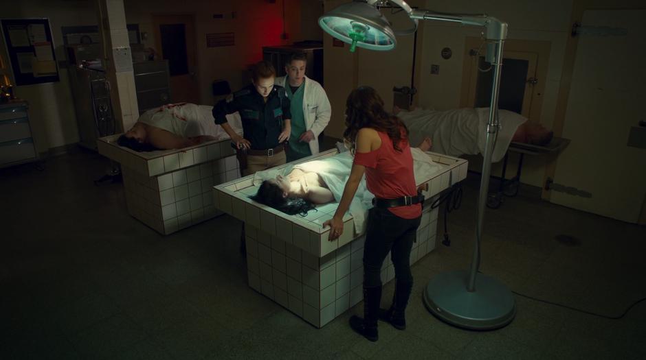 Nicole, Dr. Reggie, and Wynonna look down at the body of the murdered woman.