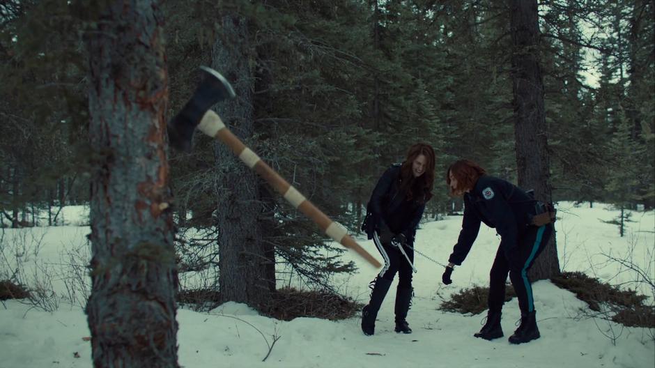 Wynonna sstruggles to unjam Peacemaker while handcuffed to Nicole as an ax hits a nearby tree.