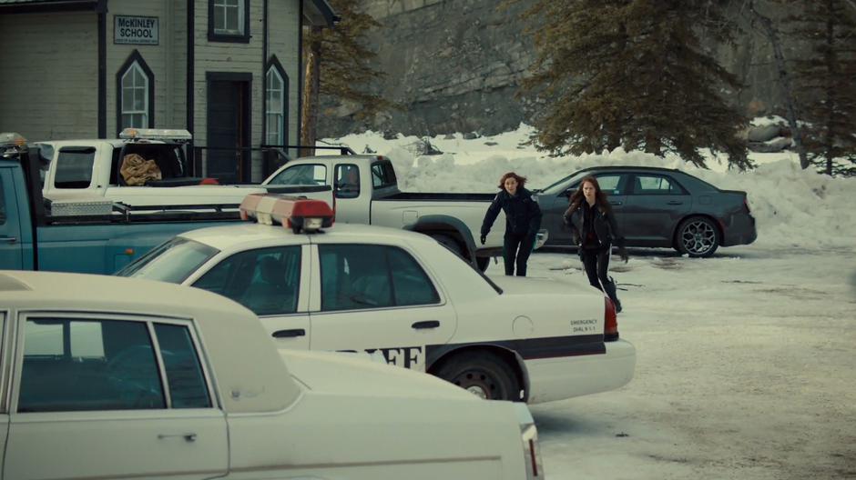 Nicole and Wynonna run low to the ground over to the stolen squad car.