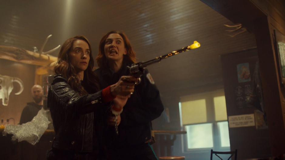 Wynonna holds out a glowing Peacemaker while Nicole yells at her to run.