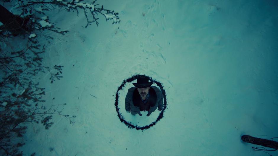 Doc stands in the middle of a circle in the forest looking up at the sky.