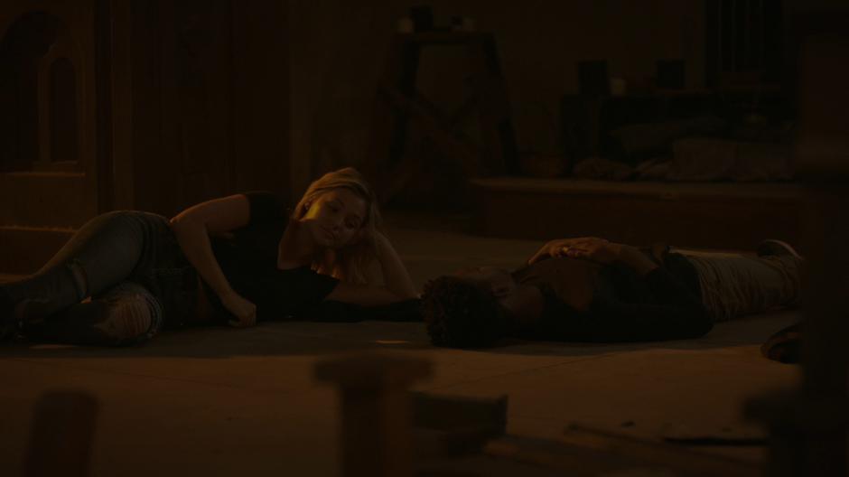 Tandy and Tyrone lie on the floor next to one another talking.