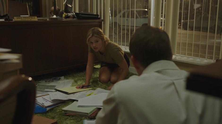 Tandy kneels on the floor with Greg looking over his evidence on Roxxon.
