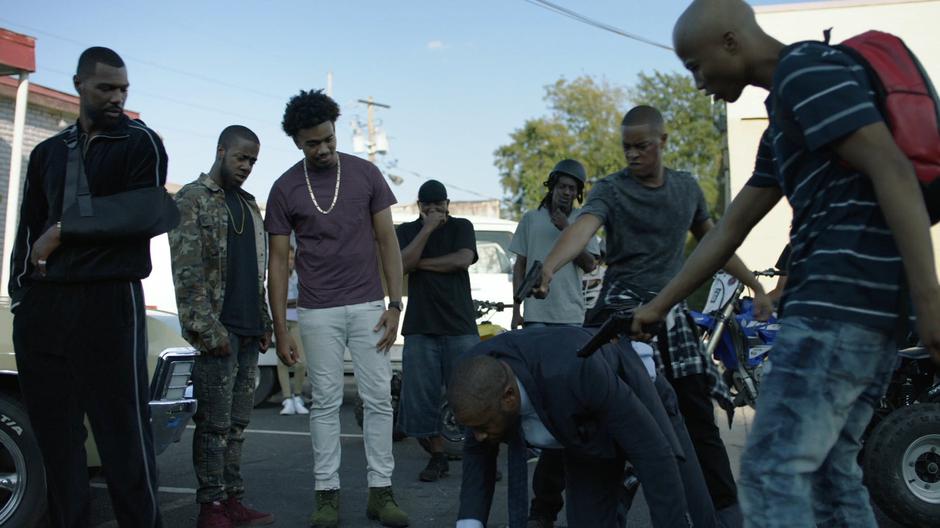 Lala watches as several gang members point their guns at Jefferson after he was knocked to the ground.