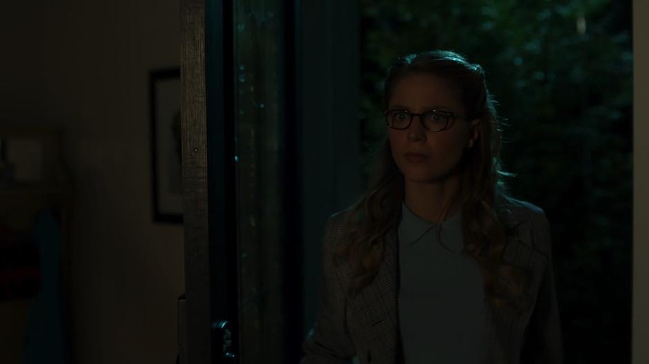 Kara walks in through the front door of the house.