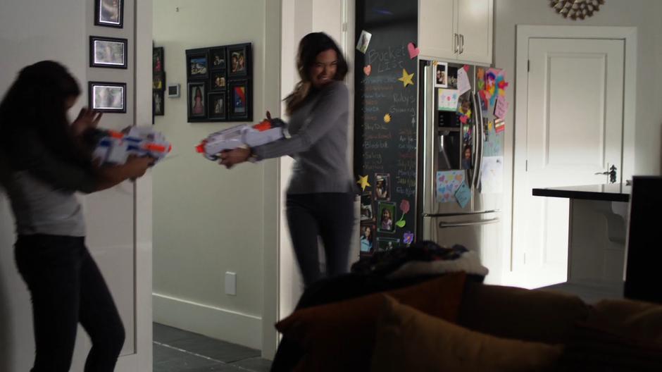 Ruby and Sam shoot each other with Nerf™ guns in the living room.
