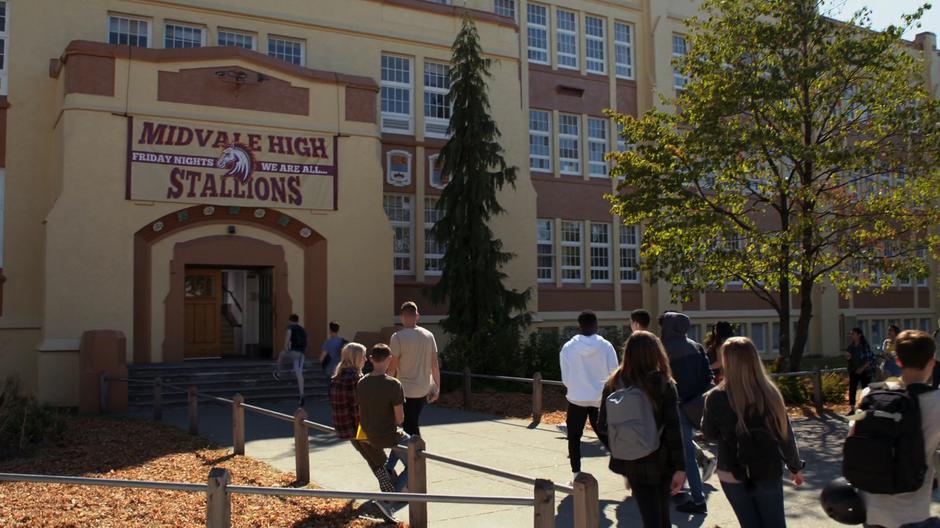 Students walk in through the front door of the school in the morning.