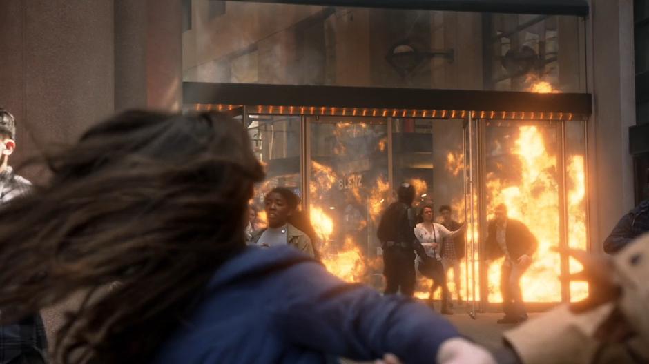 A woman runs behind James as he runs back towards the burning building.