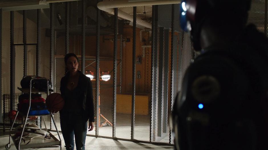 Zari holds a basketball while talking with Ray in the basement.