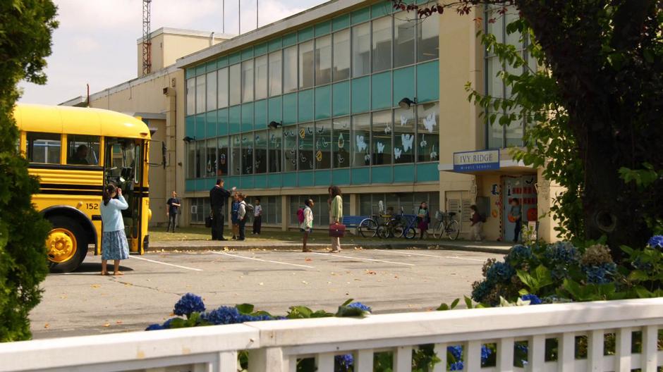 Kids walk out to the building to the school bus.