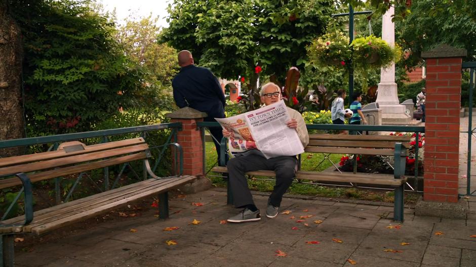 Stein watches young Ray while pretending to read a paper while Mick stands behind him looking the other direction.