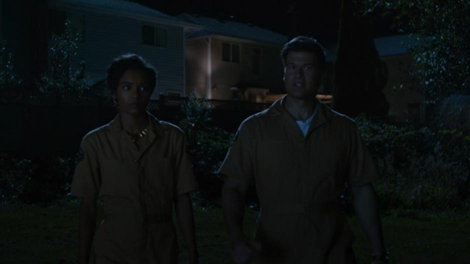 Amaya and Nate walk through the backyard disguised as Animal Control agents.