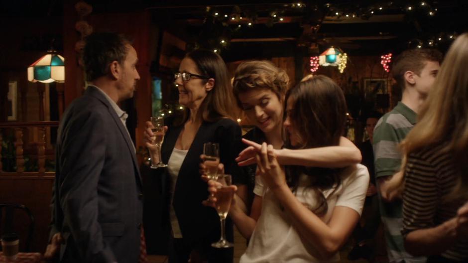 Nina looks at the right on Izzy's finger while everyone celebrates.
