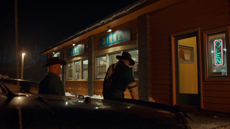 Establishing shot of the front of the restaurant as two men walk up to the door.