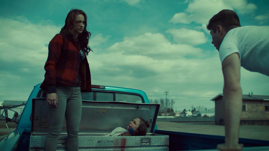 Charlie looks over at Waverly pops up gagged head up out of the trunk on the back of the truck after Wynonna pulls up the lid.