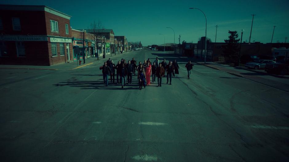 Wynonna and Mercedes walk down the street at the front of a large group of Revenants.