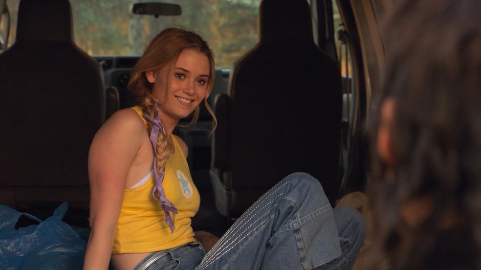 Karoline turns around in the back of the truck and smiles at Nico.