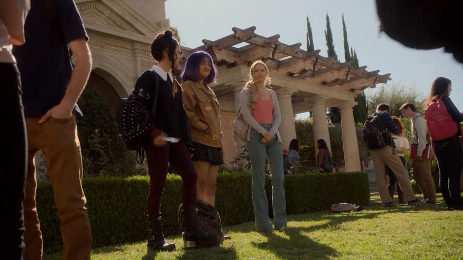 Nico, Gert, and Karolina stand together and chat in the yard before school.