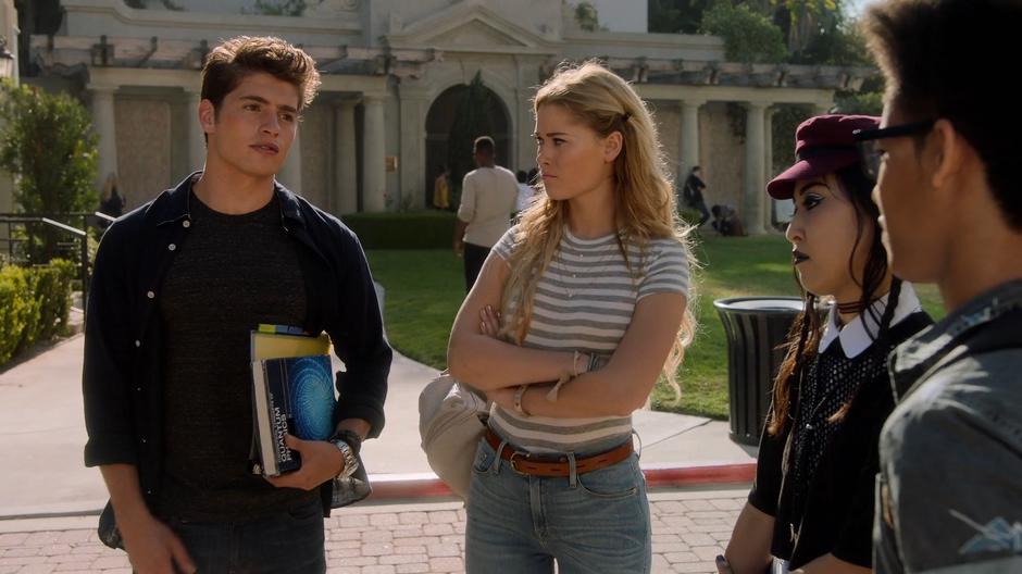 Karolina, Nico, and Alex look at Chase as they talk outside the school.