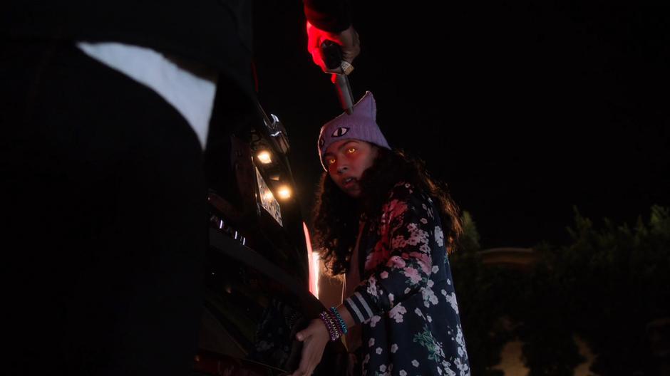 Darius Davis holds his gun at Molly's head while she lifts his car into the air.