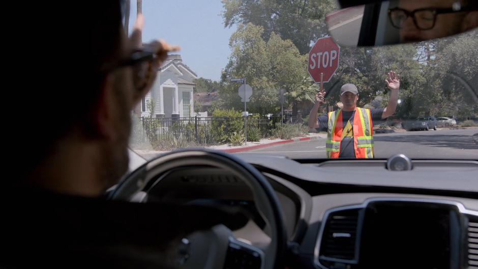 Dale stops his car at the intersection as the crossing guard holds up a stop sign.