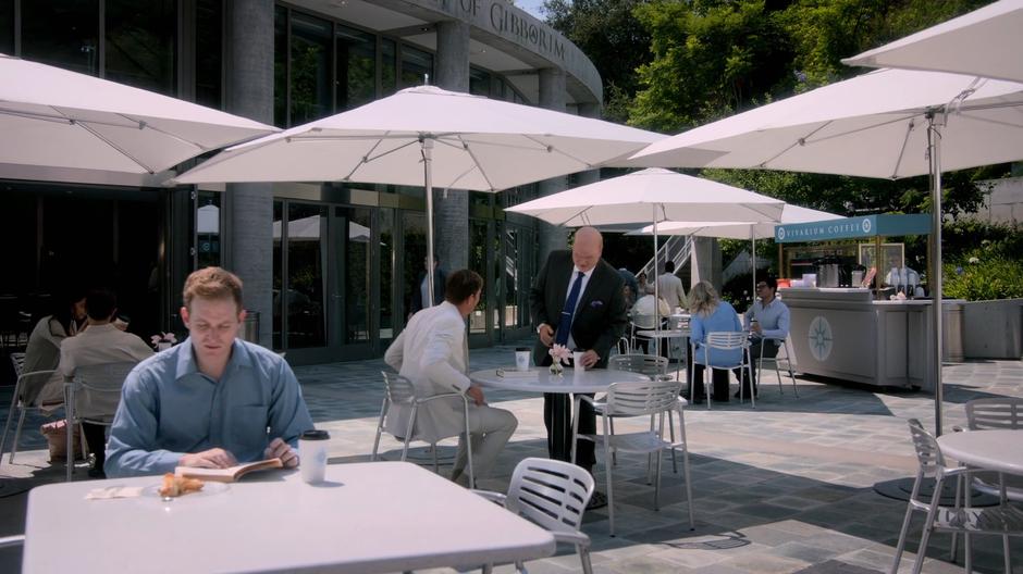Frank sits down at a table outside with Phil, his agent.