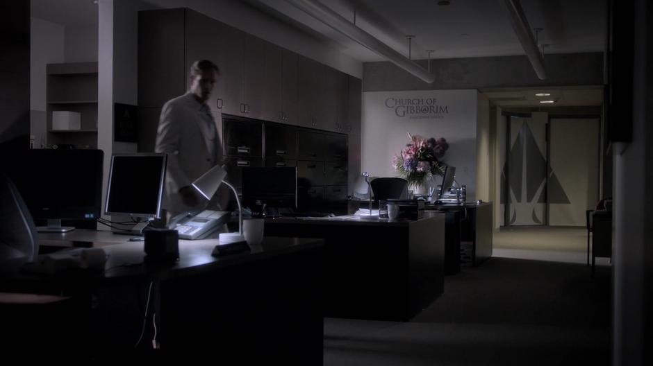 Frank walks through the darkened chruch offices in the evening.
