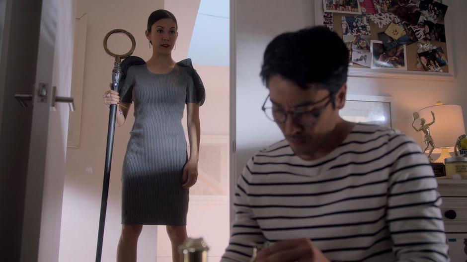 Tina stands in the doorway of Amy's room while Robert tries to repair the broken trophy.