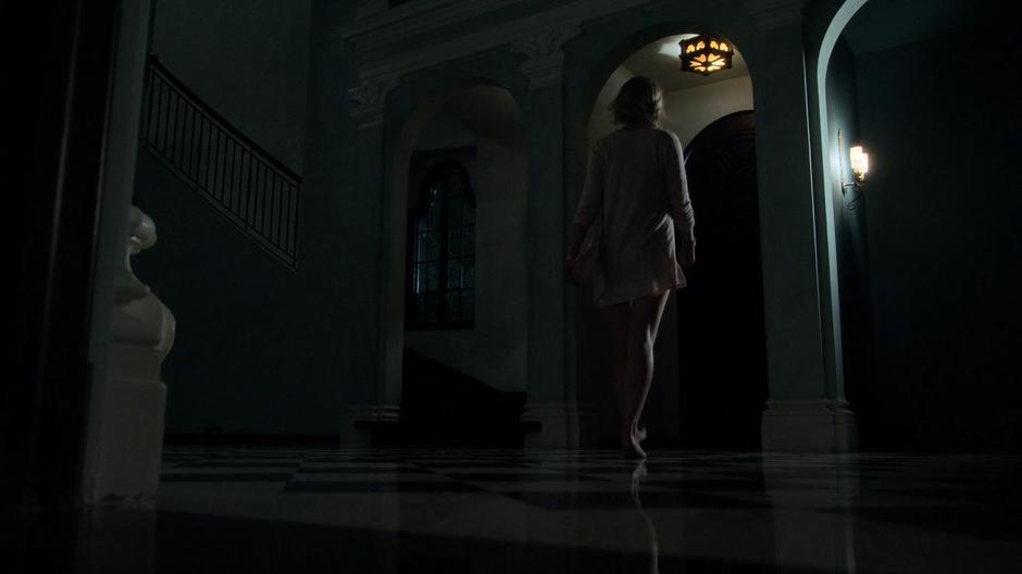Karolina walks through the main hall to the back door.