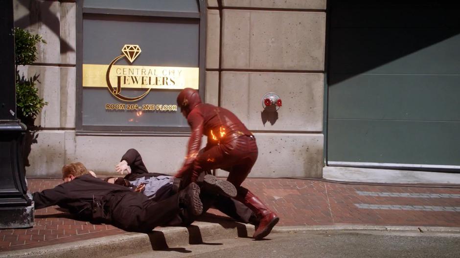 Barry sets the two armored truck guards safely down on the ground.