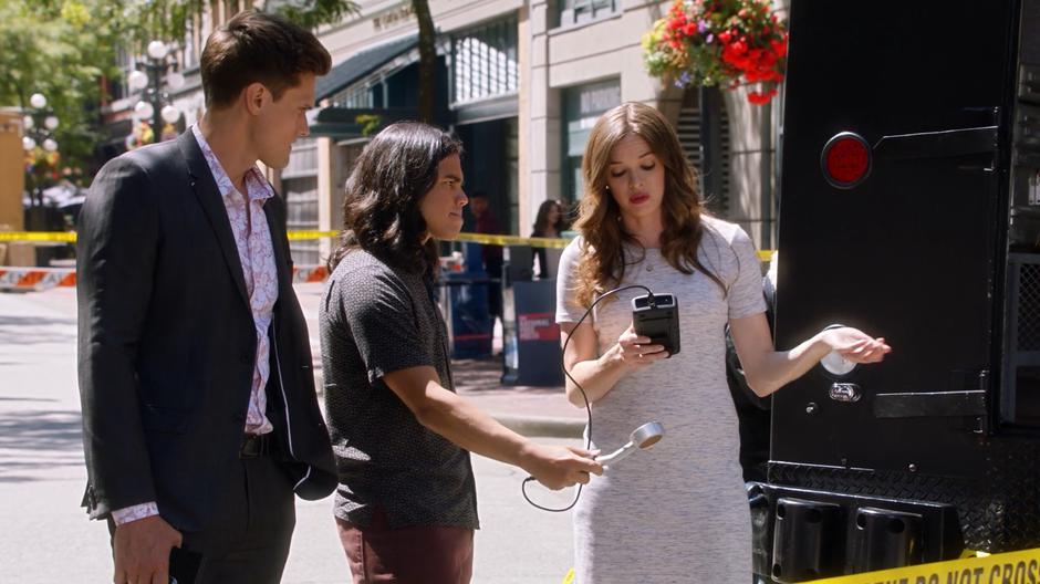 Ralph watches as Cisco shows Caitlin the dark matter readings around the back of the armored truck.