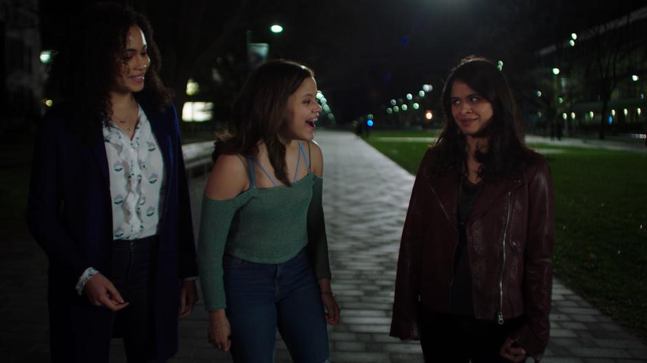 Macy and Maggie smile over at Mel as they are walking down the pathway at night.