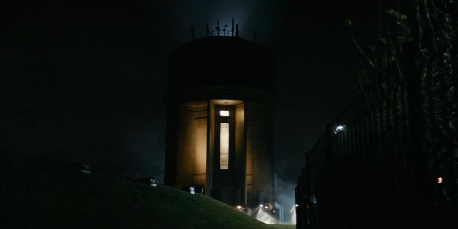 A strange light emenates from the top of the water tower at night.
