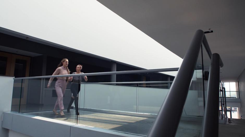 Lena checks to make sure Kara is okay as they cross the bridge to the other side of the lobby.